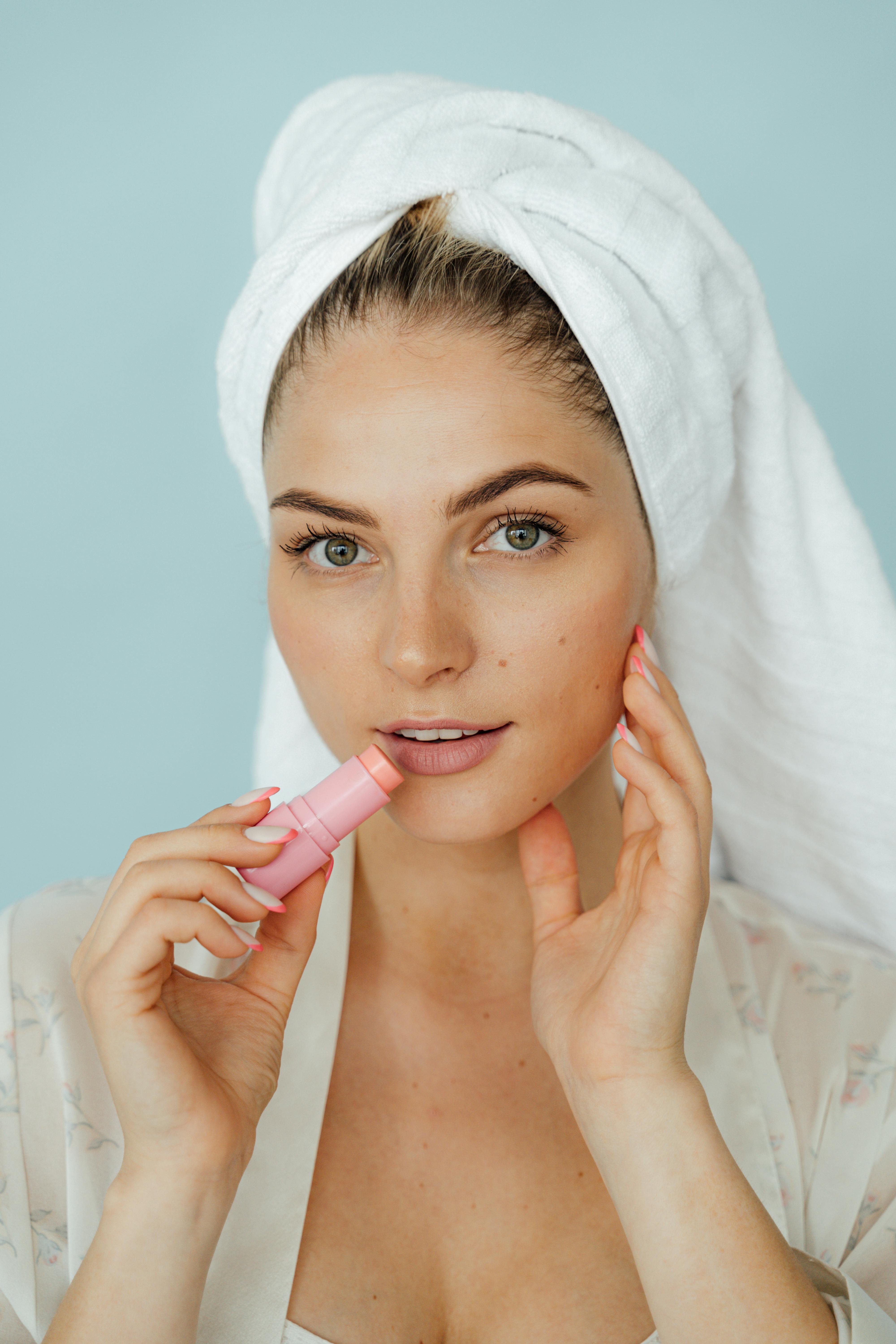 这幅宁静的肖像描绘了一位涂着粉色口红的女士，突出了她的护肤习惯