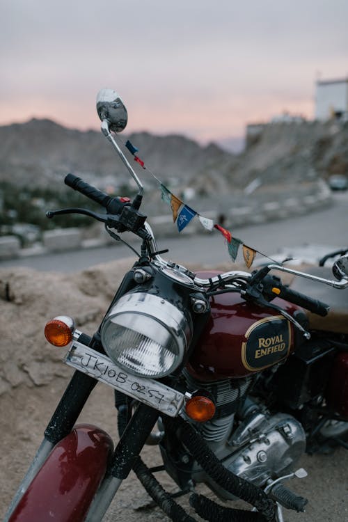 Retro motorcycle parked on dusty rural road in mountainous valley against sunset sky