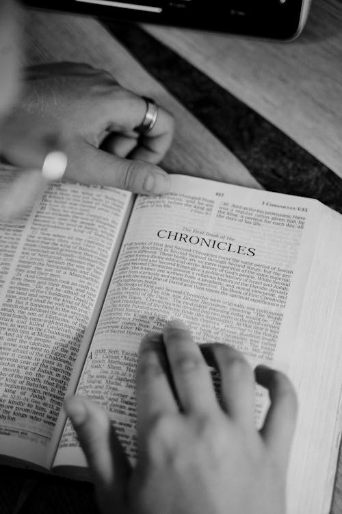 Grayscale Photo of a Person Reading a Bible