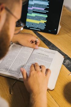 一本打开的圣经旁，放着一台用于查阅编年史的数字平板电脑