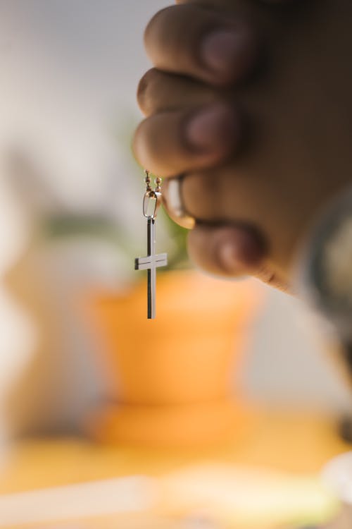 Close-Up Shot of a Person Holding a Cross Pendant