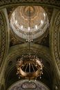 From below of chandelier and ornamental domed ceiling of ancient Coronation Cathedral decorated with icons and golden details in Alba Iulia