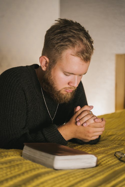 Close-Up Shot of a Bearded Man in Black Knitted Sweater Praying