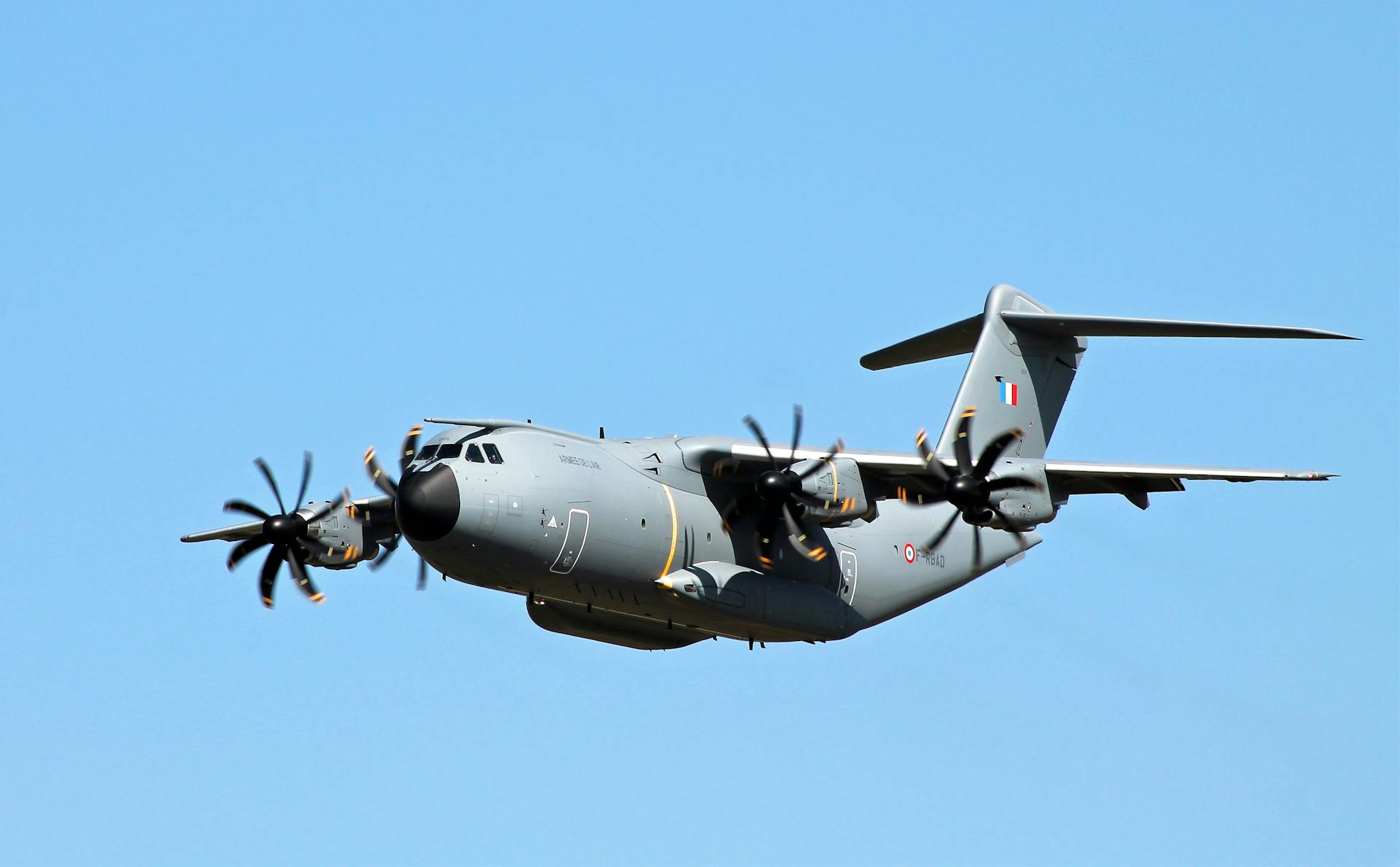 A powerful military transport aircraft soaring through a clear blue sky.