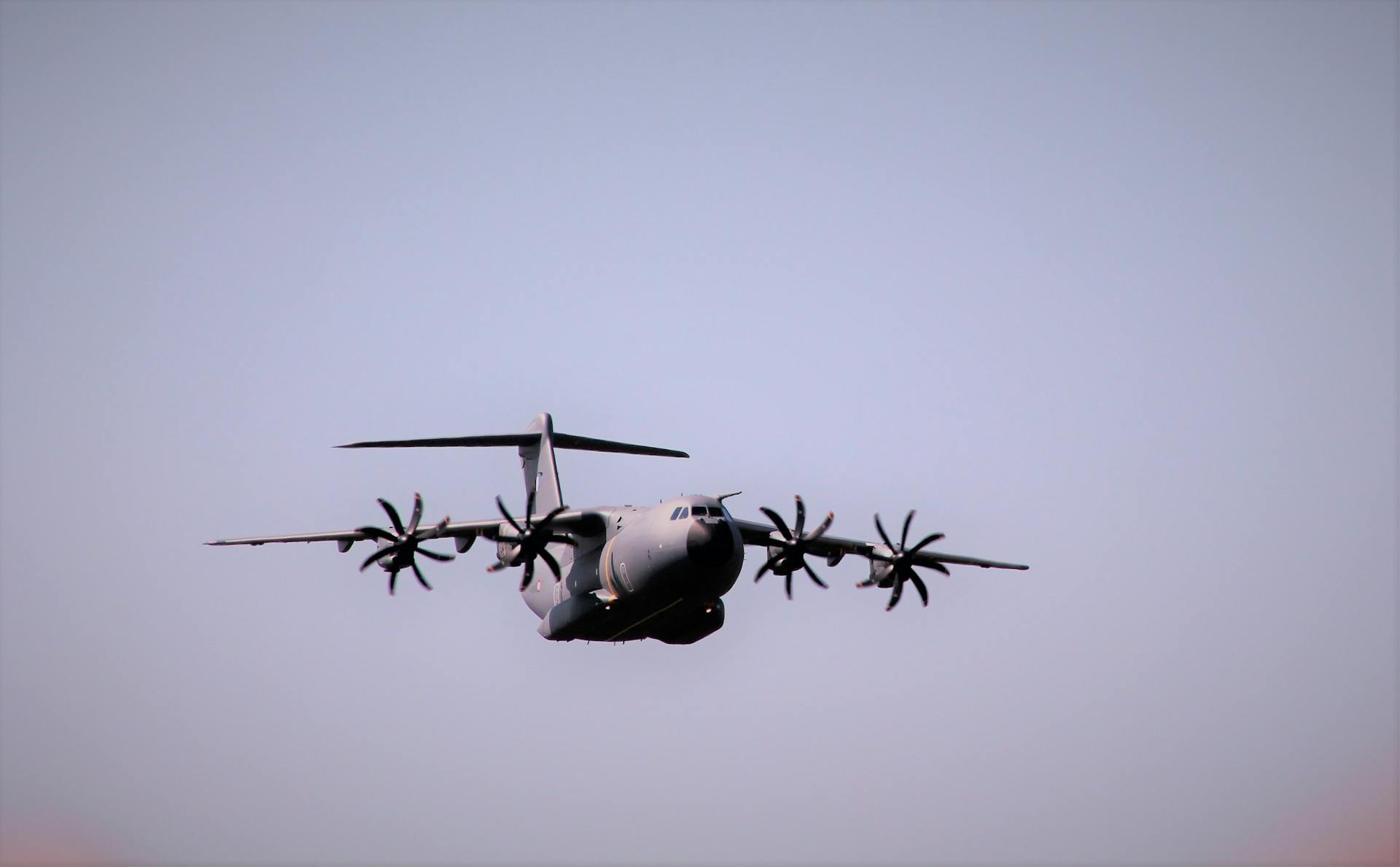 A large military transport aircraft flying against a clear sky background.