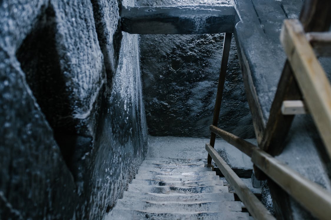 Free From above of aged stone stairway covered with salt in ancient cave with shabby walls and wooden railings in Registry Chamber of Salina Turda mine Stock Photo