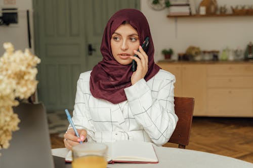 Close-Up Shot of a Woman with Hijab Having a Phone Call while Sitting on a Chair