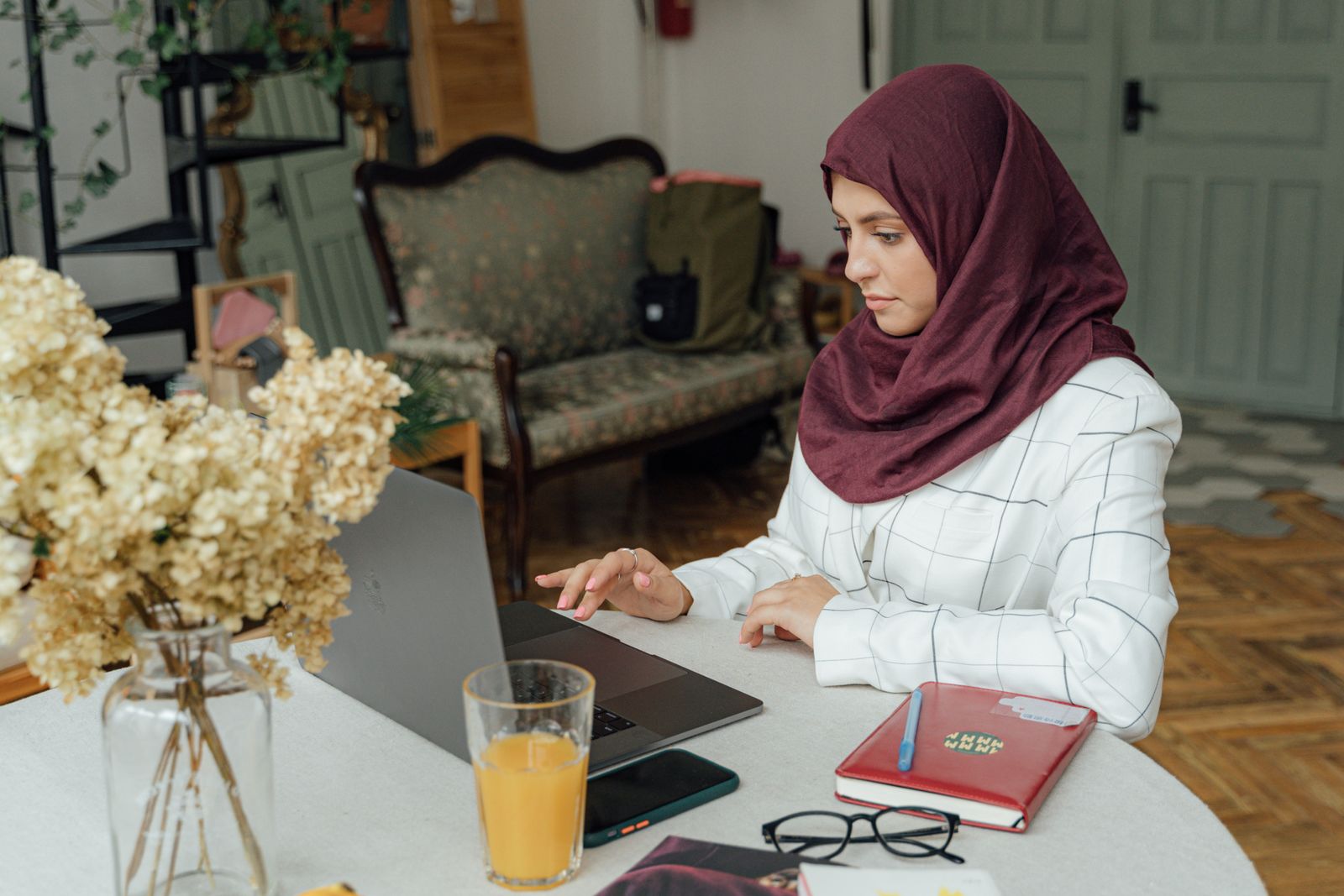 Woman in a hijab using a laptop at a desk.