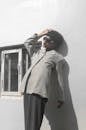 Man in Gray Coat Standing Near White Wall