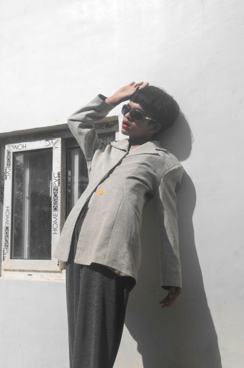 Free Stylish individual standing outdoors in sunlight against a white wall. Stock Photo