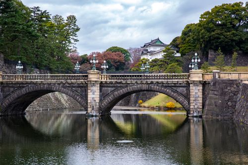 Free Elegant stone bridge leading to Tokyo's Imperial Palace, surrounded by lush greenery and serene waters. Stock Photo