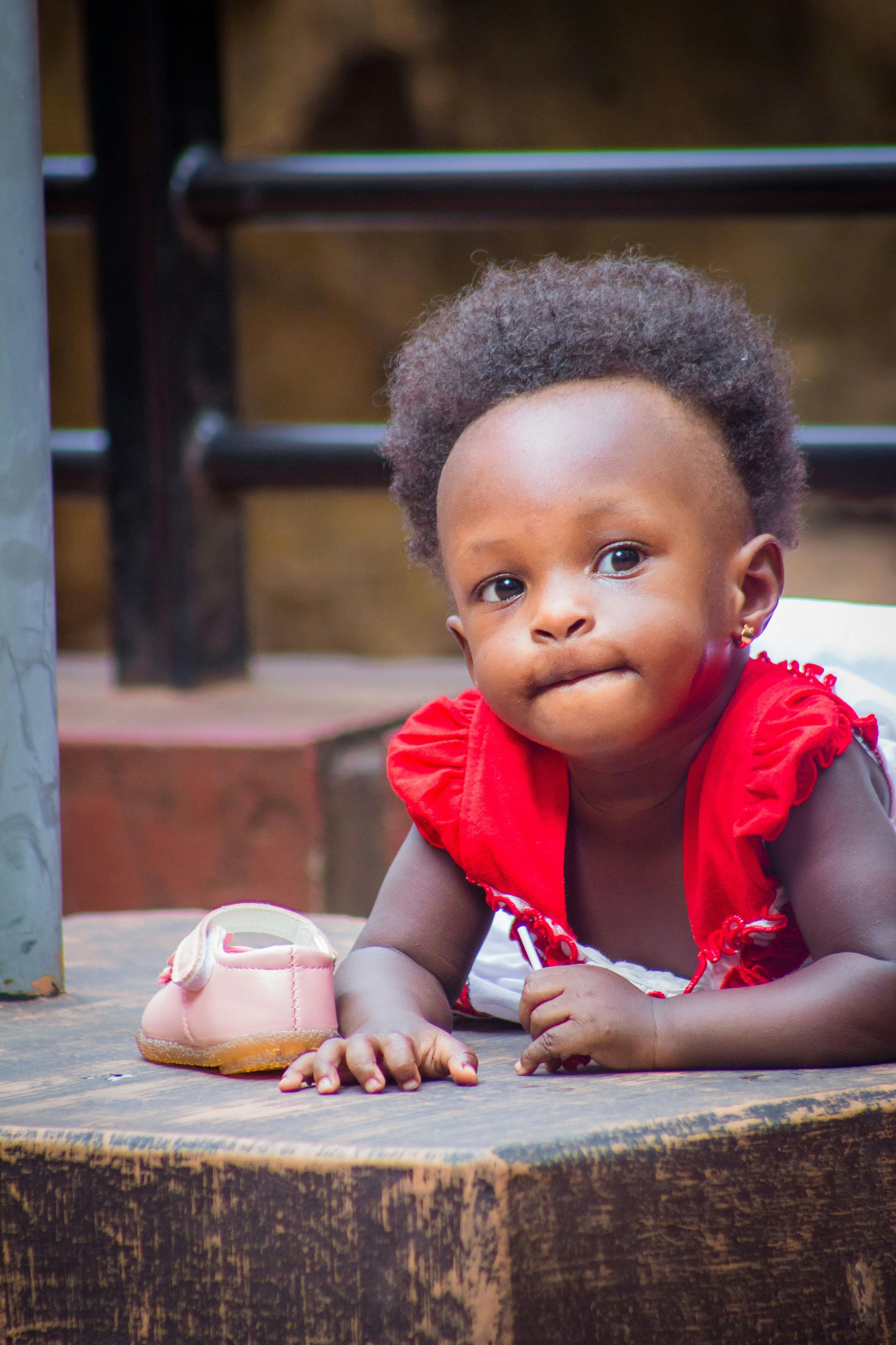 Charming baby girl crawling on the floor in a vibrant red dress, showcasing innocence and curiosity.