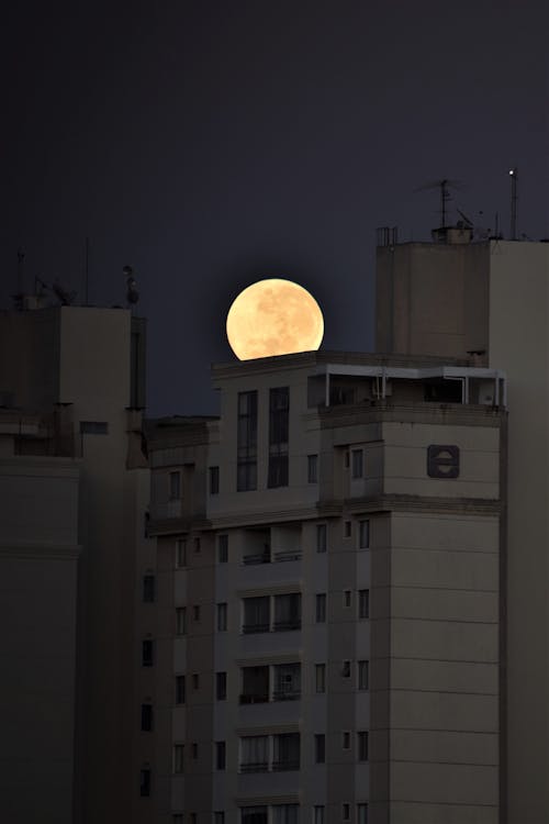 A Clear and Bright Full Moon behind a Building