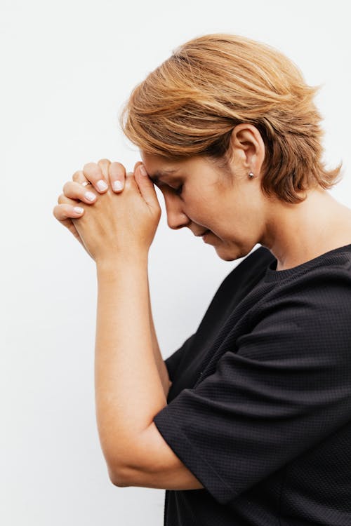 Close-Up Shot of a Woman in Black Shirt Praying 