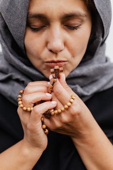 一位戴着头巾的女人闭着眼睛，用念珠祈祷，象征着信仰与反思