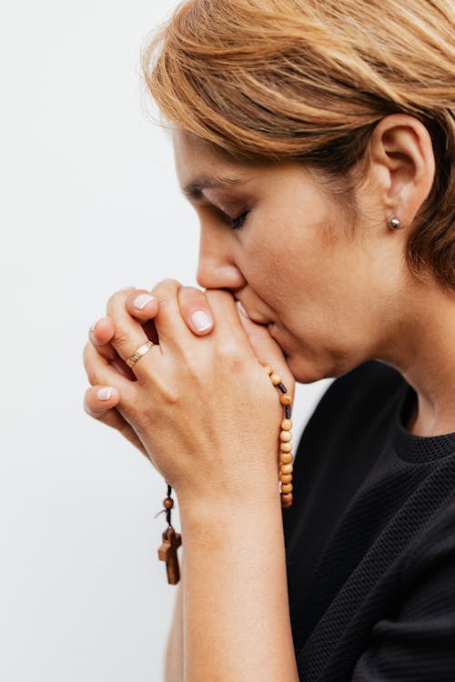 Close-Up Shot of a Woman in Black Shirt Praying 
