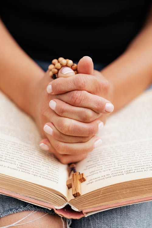 Close-Up Shot of a Person Praying while Holding a Rosary
