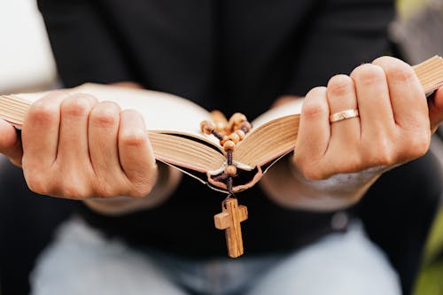 Free Close-Up Shot of a Person Reading a Book with Rosary Stock Photo