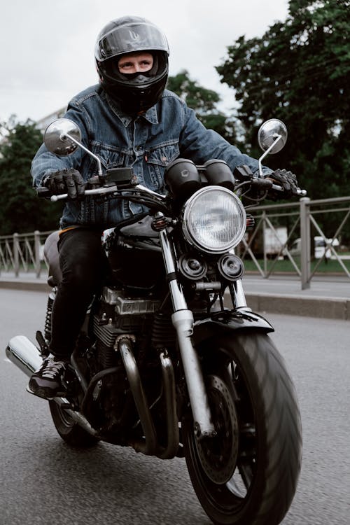 A Man in Denim Leather Jacket Riding a Black Motorcycle