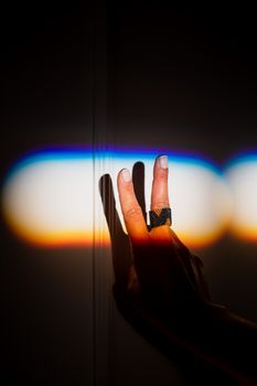 特写镜头中，一只手映衬着彩虹光背景