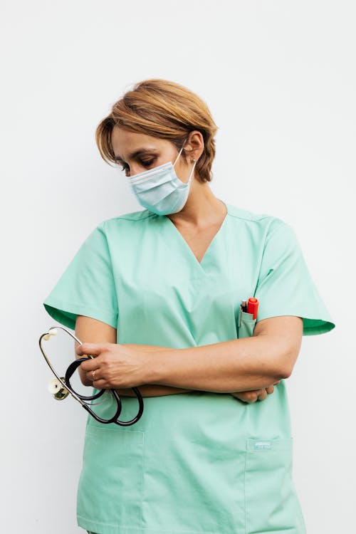 A Woman Wearing a Face Mask while Holding a Stethoscope