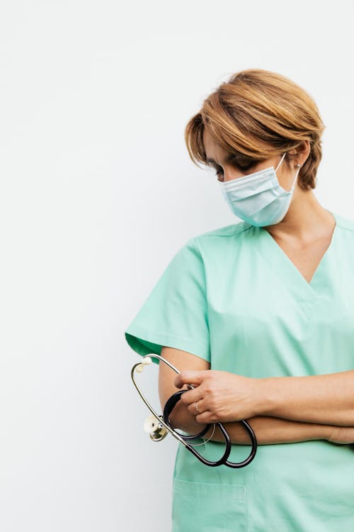 
A Woman Wearing a Face Mask while Holding a Stethoscope