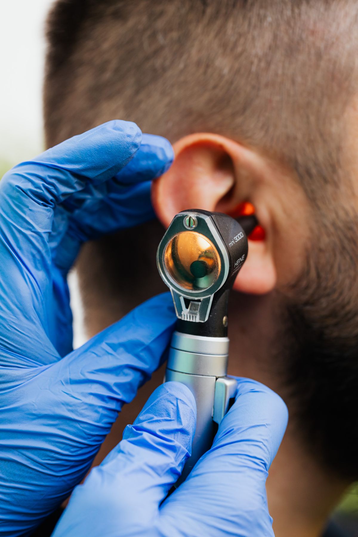 Audioprothésiste réalisant une otoscopie sur l'oreille d'un patient avant appareillage