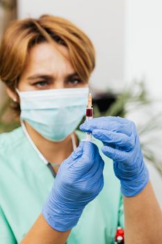 一名穿着防护服的医护人员正在准备血液样本注射器