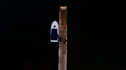 
An Aerial Shot of a Boat beside a Wooden Pier