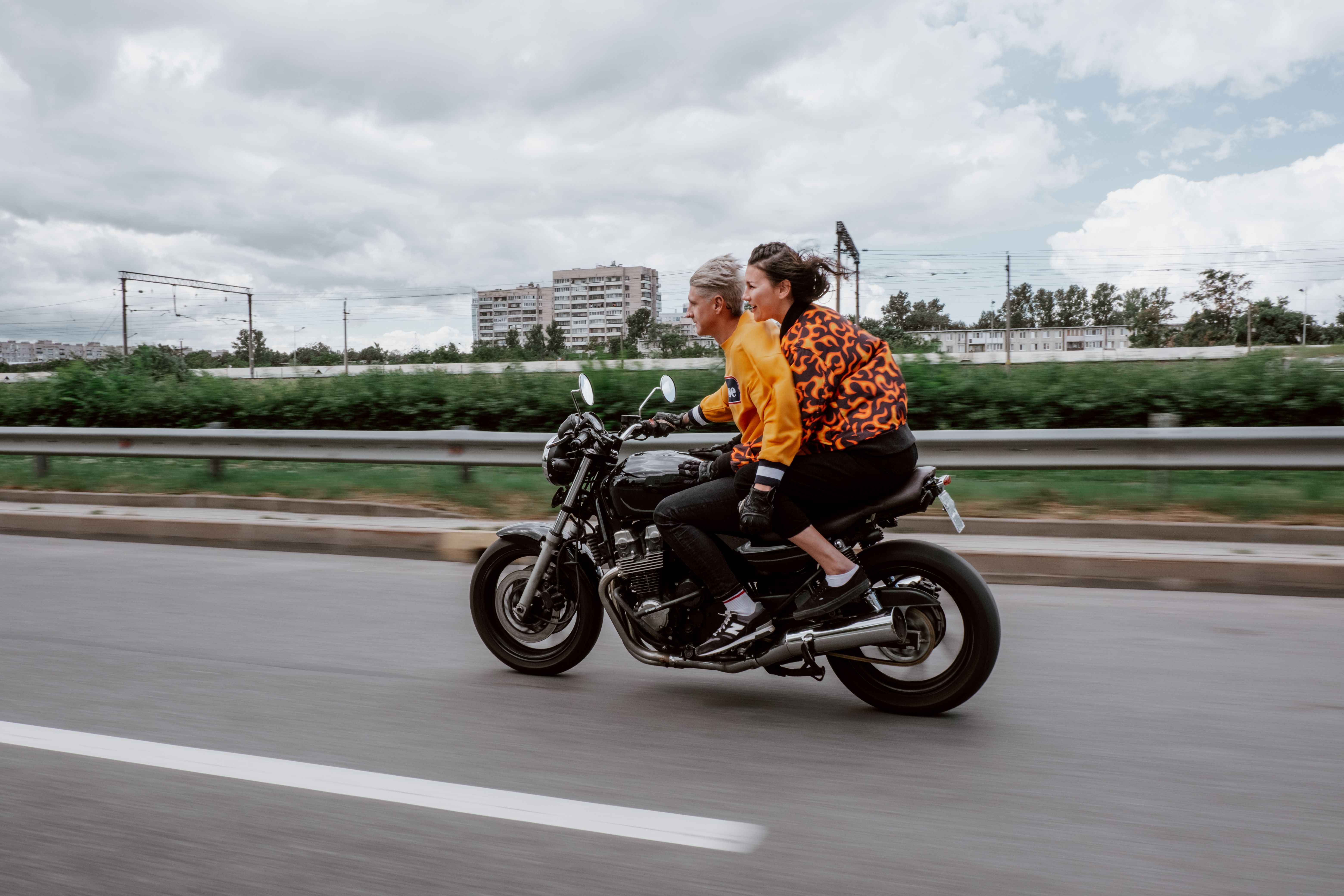 一对夫妇骑着摩托车，沿着绿树成荫的高速公路惊心动魄地骑行