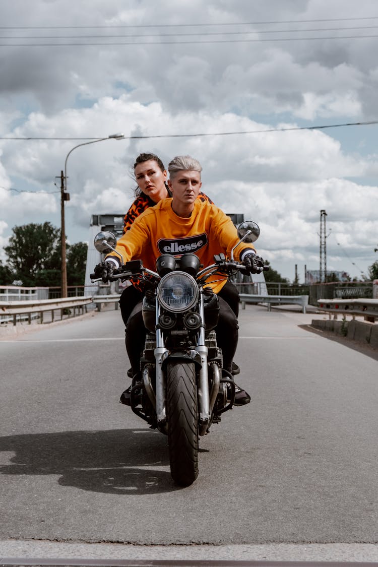 A Couple Riding A Motorcycle On The Road