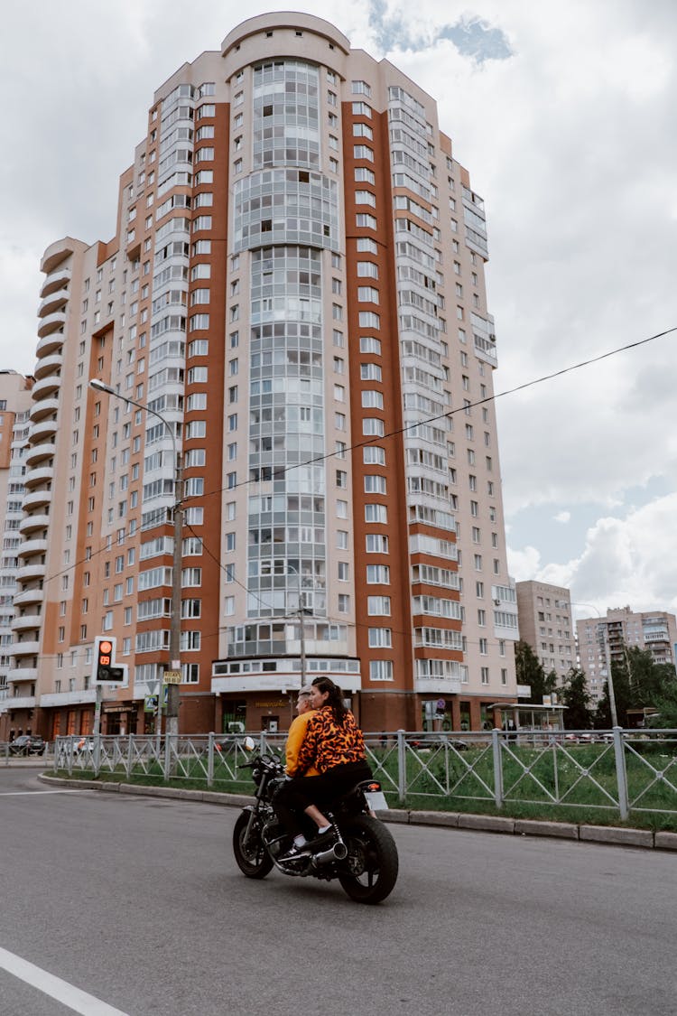 Man And Woman Riding A Motorcycle Near A Building