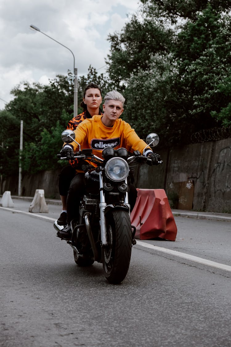 A Man And Woman Riding A Motorcycle Without Helmets