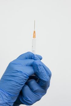 白色背景上，一只戴着手套、拿着注射器的手的特写