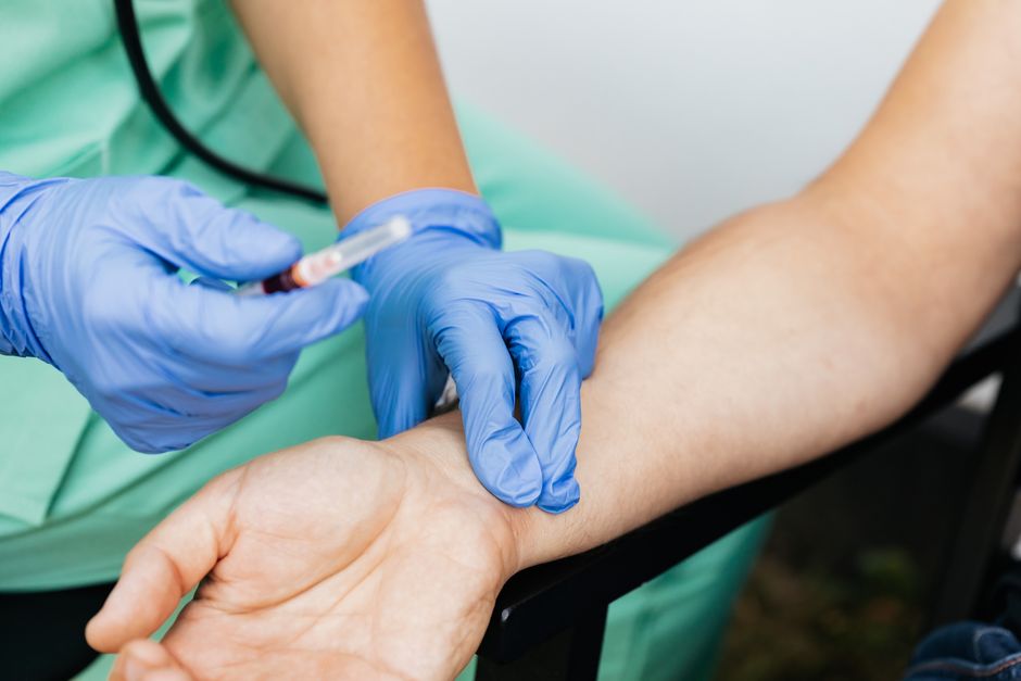 Close-up of nurse checking pulse and preparing syringe for medical use.