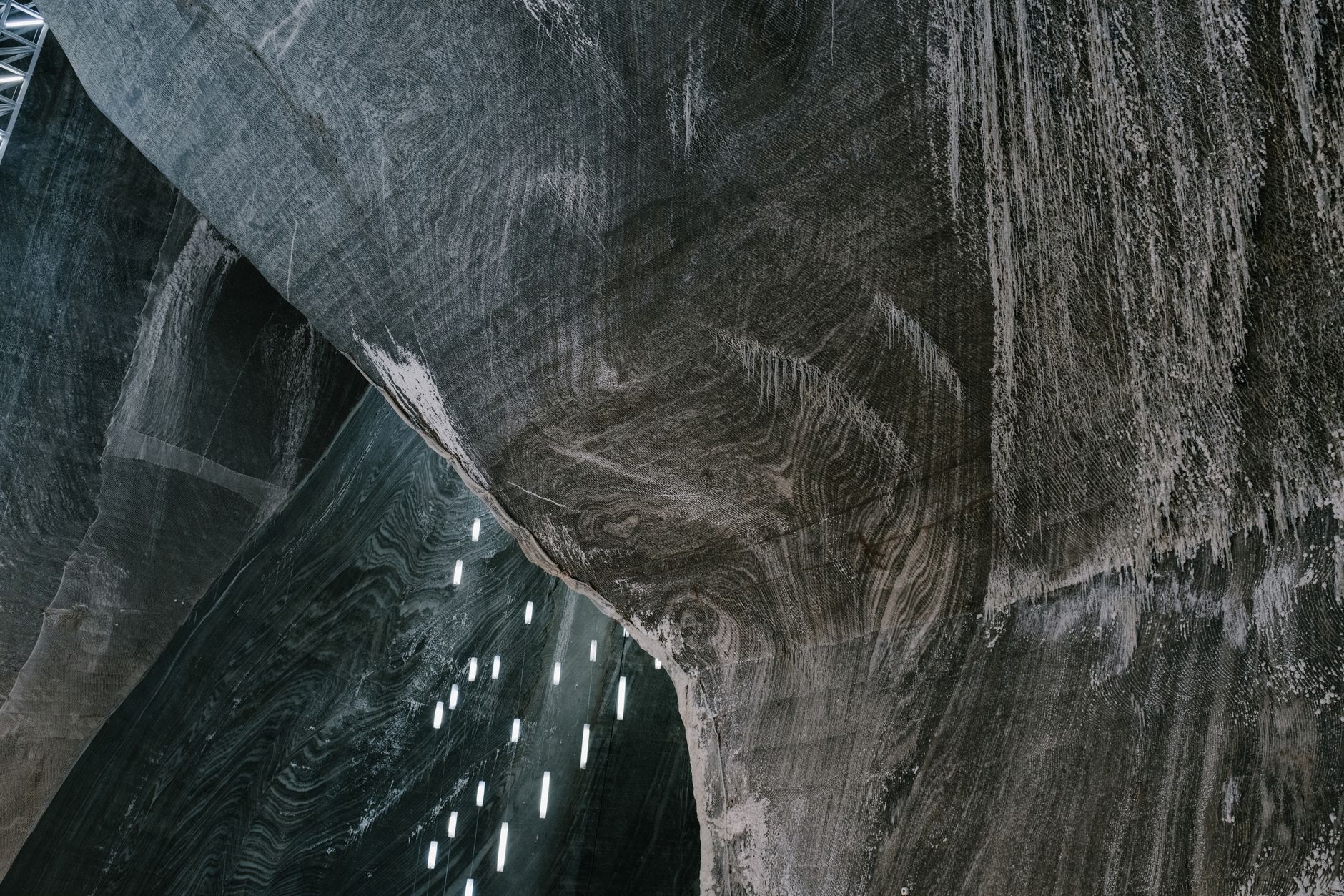 Low angle of abstract textured walls and hanging LED lamps in Salina Turda salt mine in Romania