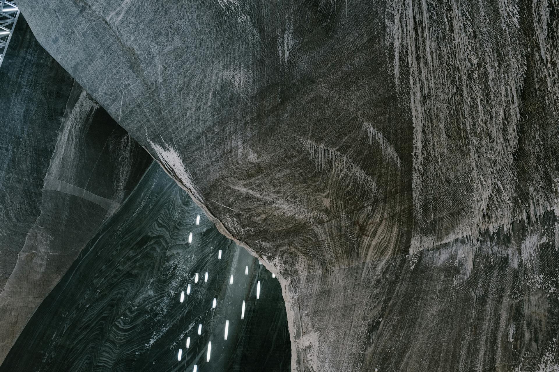 Low angle of abstract textured walls and hanging LED lamps in Salina Turda salt mine in Romania