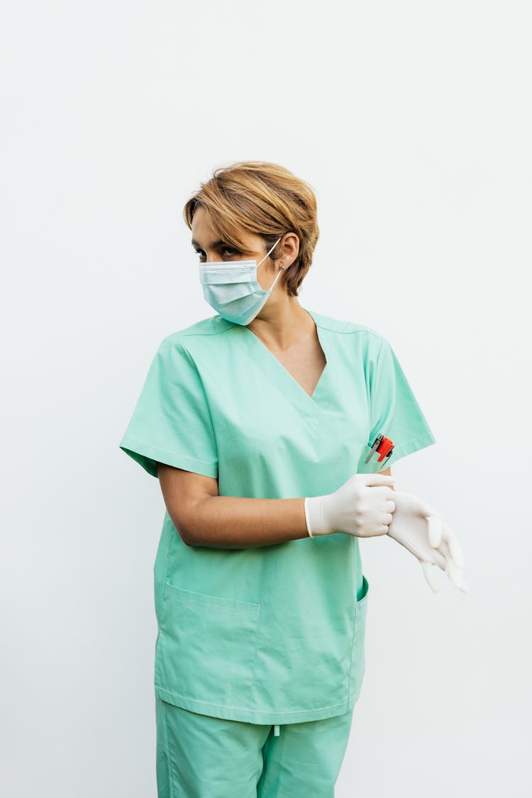 Woman Wearing Green Scrub Suit Removing Her Gloves