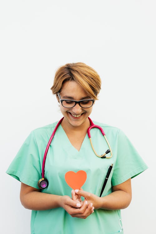 Free Doctor Wearing a Scrub Suit Holding a Paper Heart Stock Photo