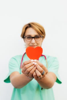 Focused healthcare worker holding a red heart, symbolizing care and compassion.