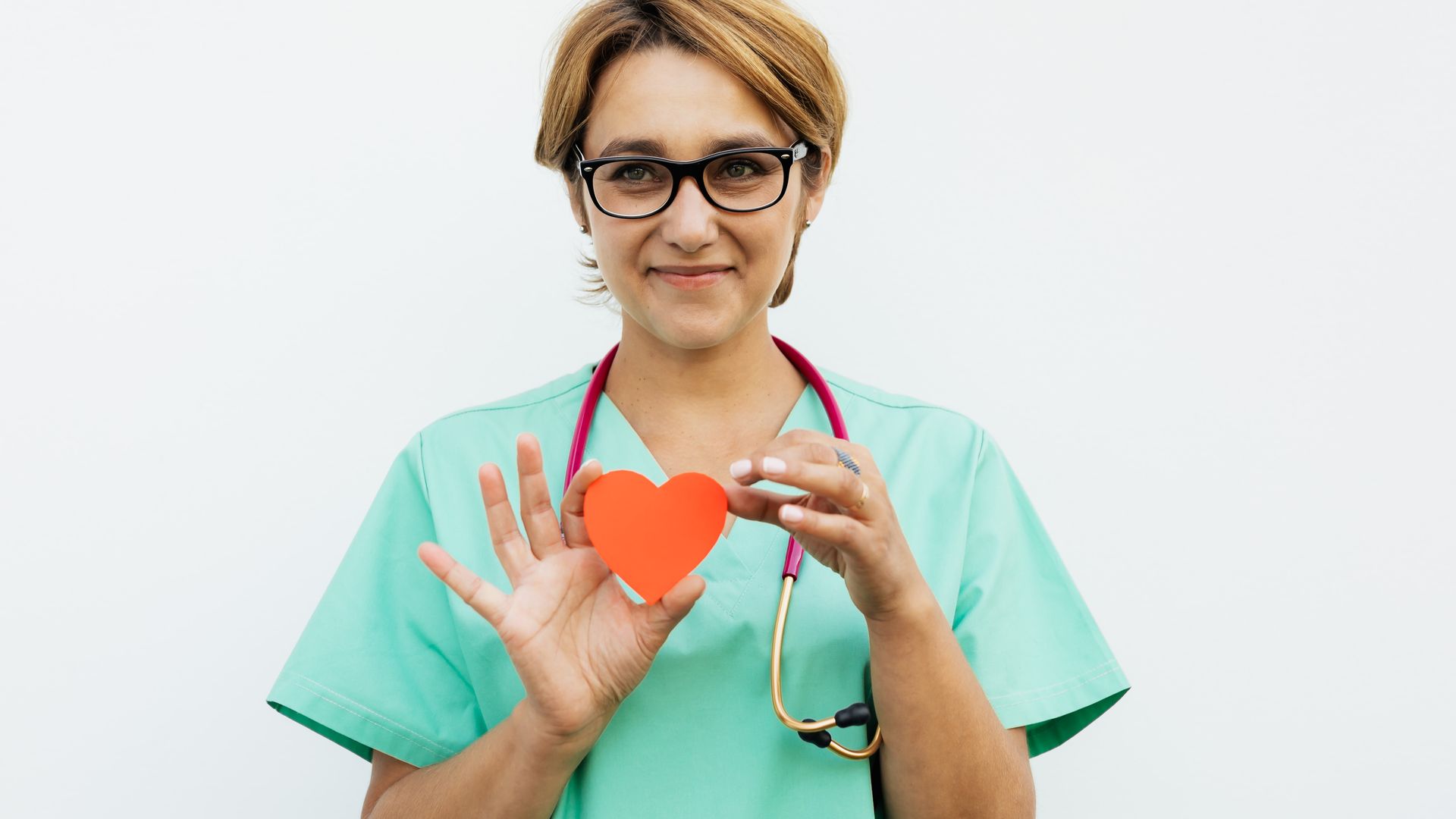 Modafinil for Nurses: Enhancing Alertness and Performance Female doctor in scrubs holding a paper heart symbol, smiling with a stethoscope around her neck — modafinil for nurses