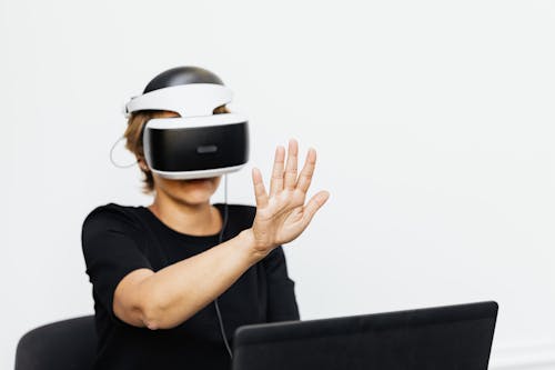 Woman Sitting in front of a Laptop and Wearing VR Goggles