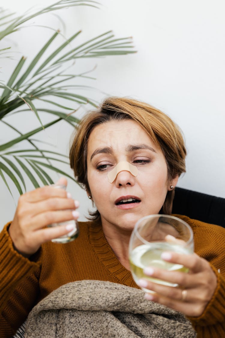 Woman In Brown Sweater Looking At Back Of Medicine Bottle 