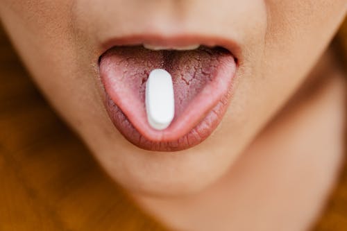 Person With White Oval Medication Pill on Mouth