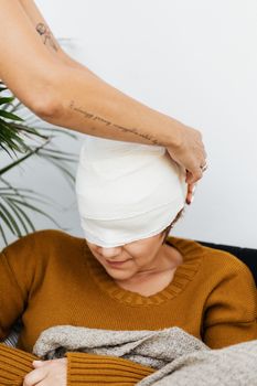 头部缠着绷带的妇女正在室内接受护理人员的照顾