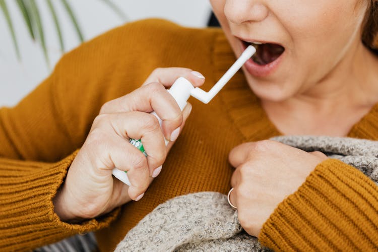 A Woman Using A Medicine Mouth Spray