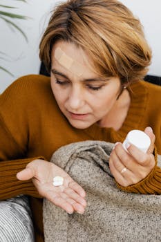 Woman with head bandage holding pills and medicine bottle, representing health care at home.
