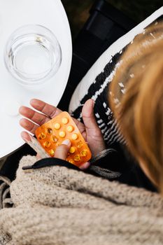 一张特写图：附近桌子上，一只手拿着药品泡罩包装，另一只手端着一杯水