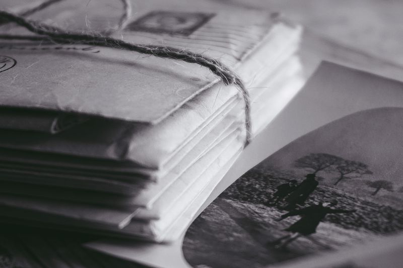 Stack of vintage letters tied with string next to a black and white photo, evoking nostalgia.