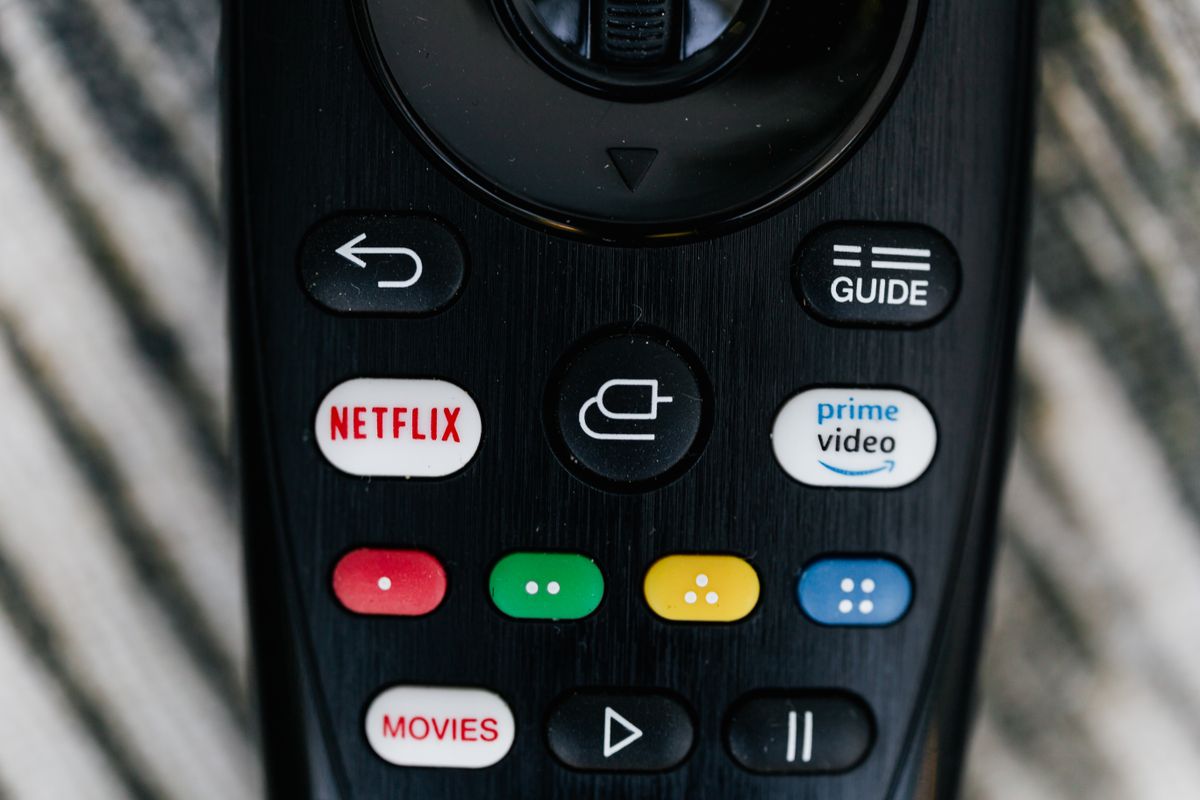 Close-up of a TV remote control with streaming service buttons